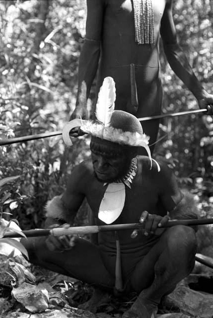 Man preparing for an Etai; whitening the decoration on his spear