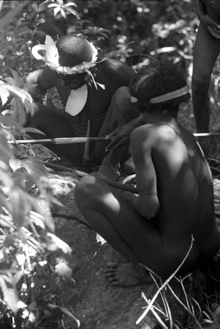 Men preparing for an Etai; whitening the decorations on their spears