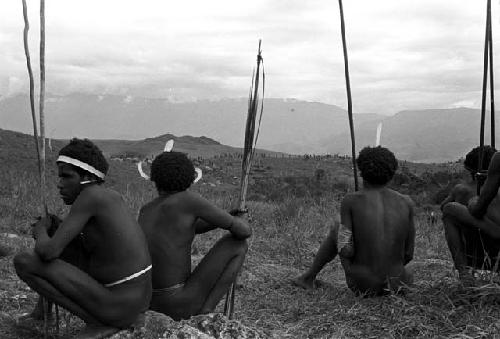 Warriors watch the distant battle with their spears in hand
