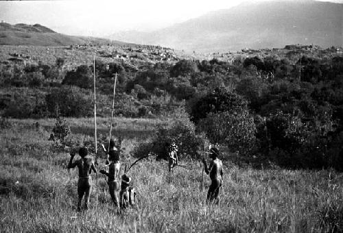 Warriors with spears watch the distant battle