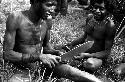 A warrior refines his arrow with a machete