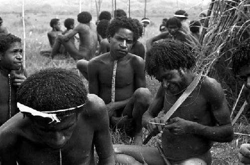 A warrior refines his arrow with a machete