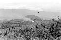 A bird sitting on long grass; fire and the Siobara in the distance