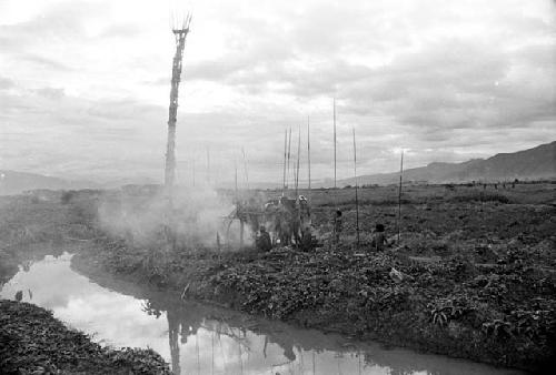 Men with spears around a burning oléa