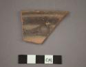 Ceramic rim sherd of bowl, black painted designs on interior