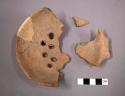 Fragments of undecorated pottery ladle with holes in bowl