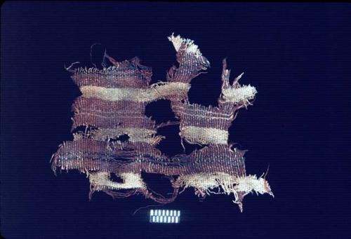 Red textile fragment with blue stripes on brown from Site 120
