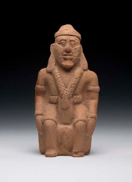 Whistle, seated male human form. Mouthpiece in elbow, one hole on bottom, window on back