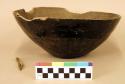 Pottery bowl. Base uneven, also rim. Surface very rough, greyish-black polishe