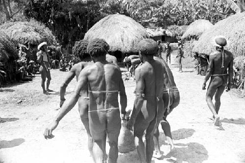 large pig being carried to in front of the honai where is laid out and butchered