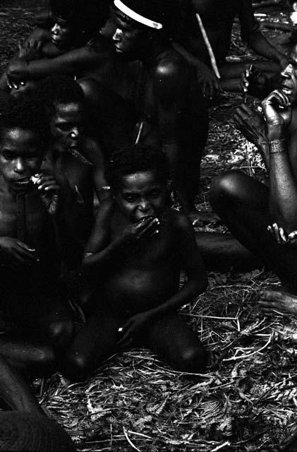 Tukom eating pig meat; group behind him doing same