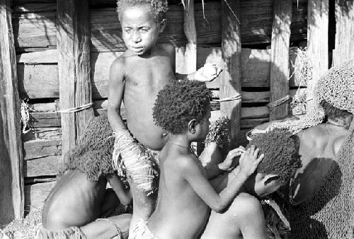 children and a woman lousing another child