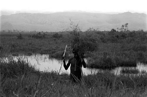 men carrying some grass to protect themselves from the rain