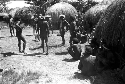 man stands holding a pig, beyond another man holding a pig waiting its turn to be killed