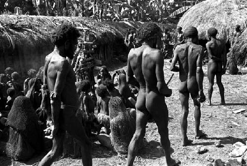 Men arriving at the funeral; pia in the left middleground