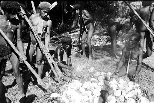 men picking up hot stones and putting them in the hakse