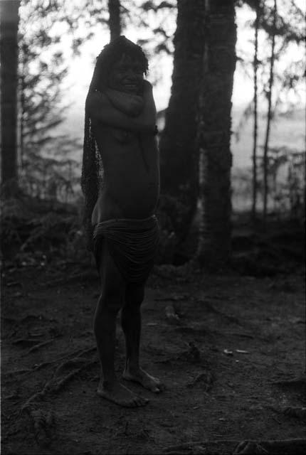 Woman standing in with her hands behind her neck