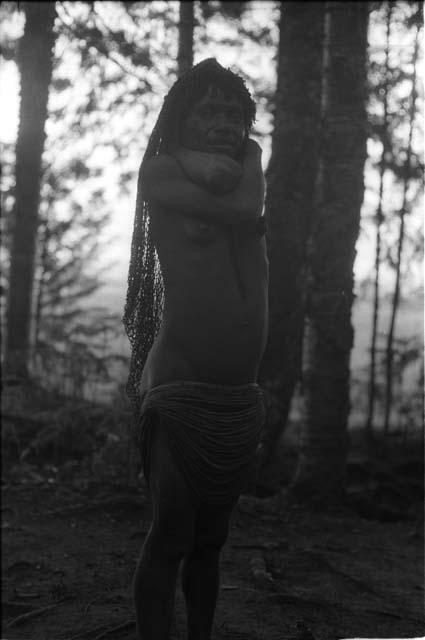 Woman standing in with her hands behind her neck