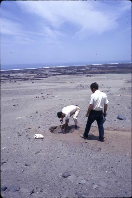 Crew at work excavating test pits in the loose dry sand at preceramic midden site on Alto de Salaverry. Andres Castillo and Michael Moseley shown at work at the site.