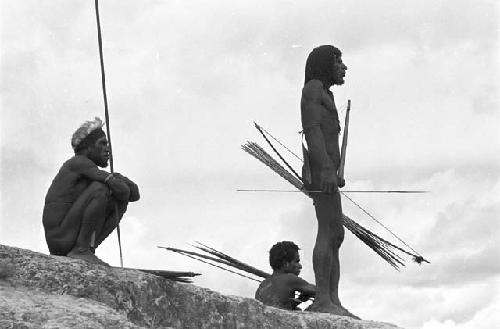 One man standing, two men crouching