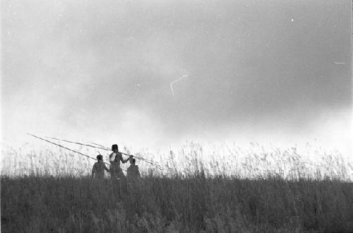 Three men in the field with poles