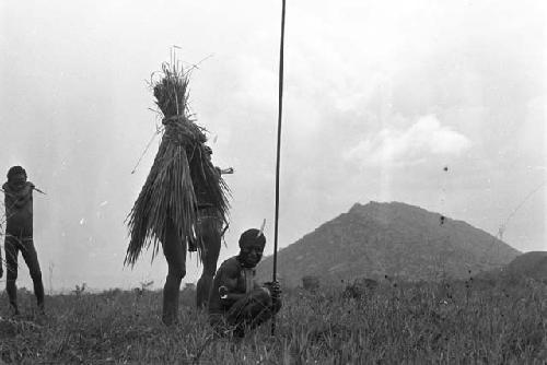 Three men standing, one crouching