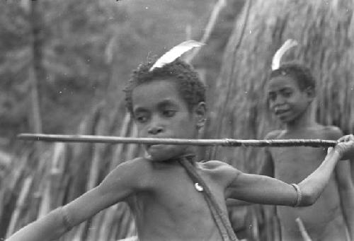 Two boys; one throwing a spear