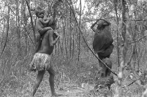 Boy carrying toddler on shoulders following a man