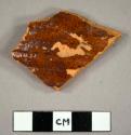 Body sherd, slightly corrugated texture. red brown glaze one side.