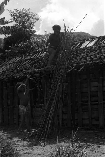 Child helps men build hunu roof