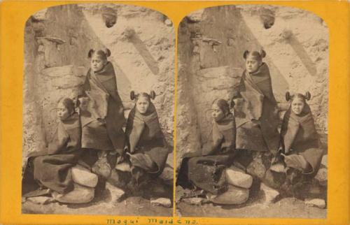 Three Hopi girls seated on rocks