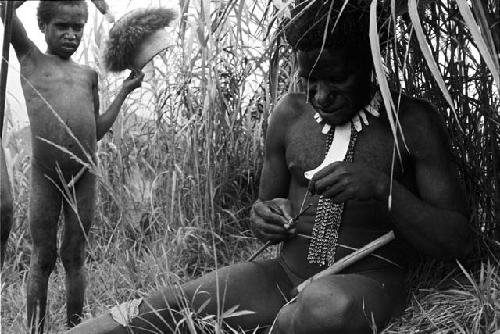 Man fixing an arrow with standing boy