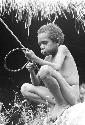 Yegé Abu sitting on a rock with a hoop and spear