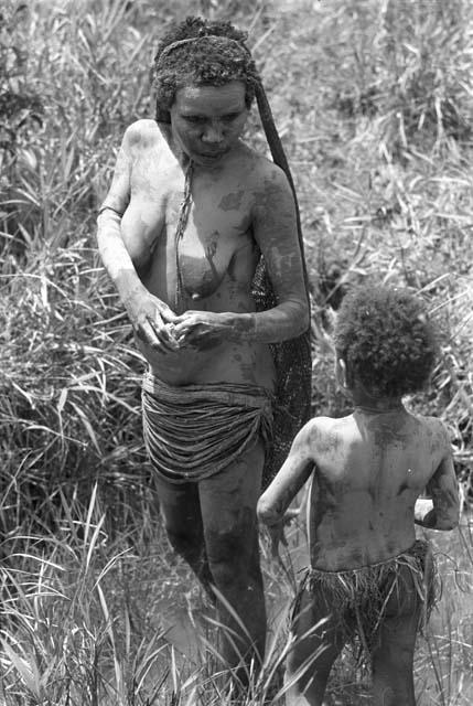 A  young girl and a woman putting clay on for Etai