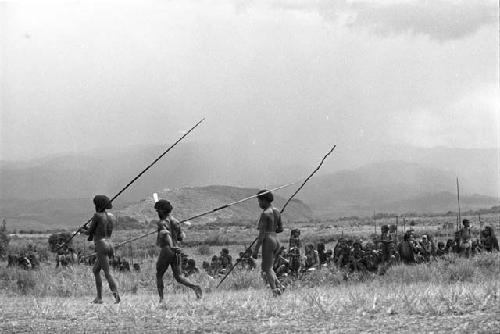 3 warriors with spears running on the Liberek during Etai; women's group behind; Siobara beyond them