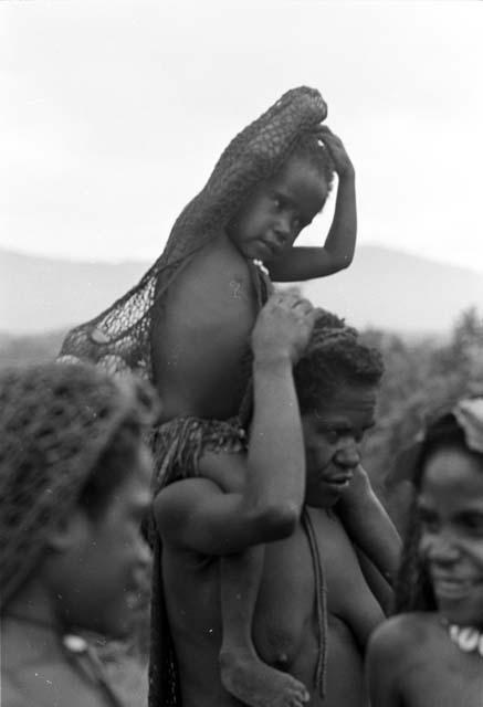 Woman carrying child on her shoulders