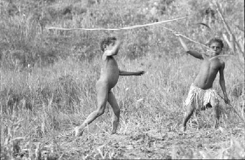 Tukom throwing his spear at a hoop;