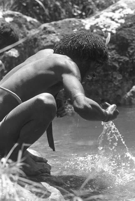 man splashes water into mouth;