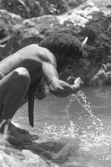 man splashes water into mouth;