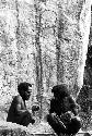 Two men beneath a rock shelter with drawings behind them