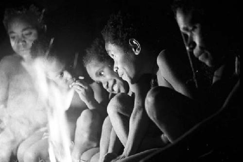 Inside hunu; women and children looking at the Coleman lamp