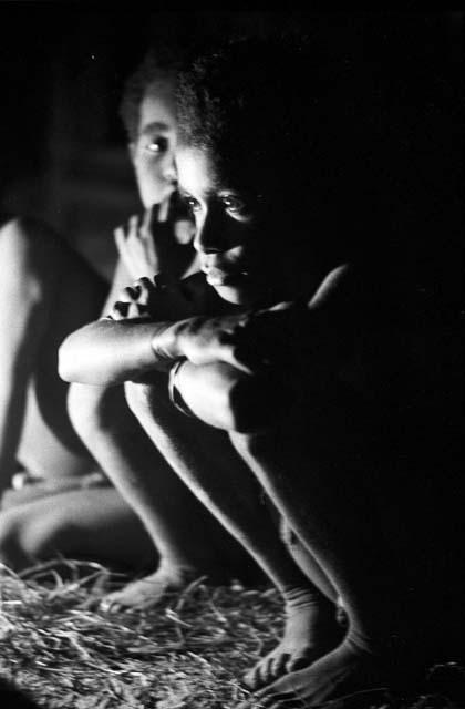 Children crouched inside the hunu at night