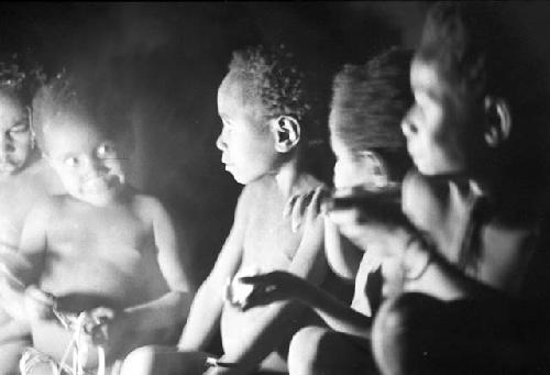 Children crouched inside the hunu at night