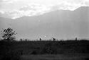 Men walking home; silhouetted on a ridge as they walk past