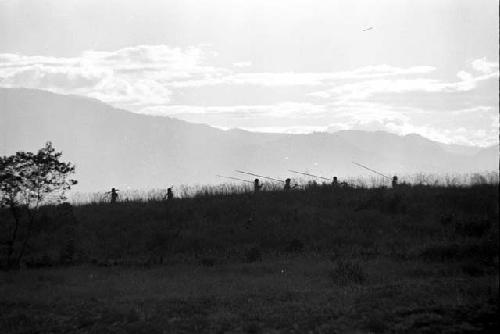 Men walking home; silhouetted on a ridge as they walk past