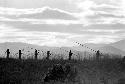 Men walking home; silhouetted on a ridge as they walk past