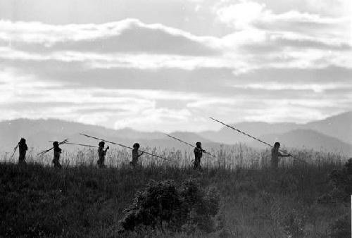 Men walking home; silhouetted on a ridge as they walk past