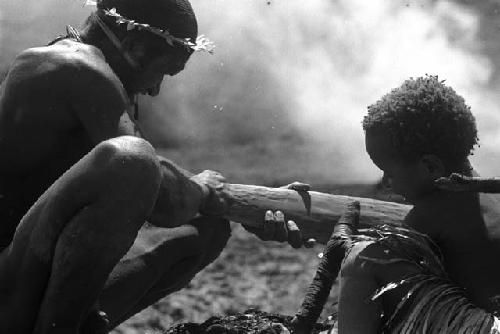 Child holds stone axe; Itlai smooths the paddle