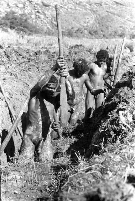 Men working in the ditch; clearing an enormous amount of trash