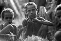 Young boys and girls eat pig at the funeral ceremony for the woman